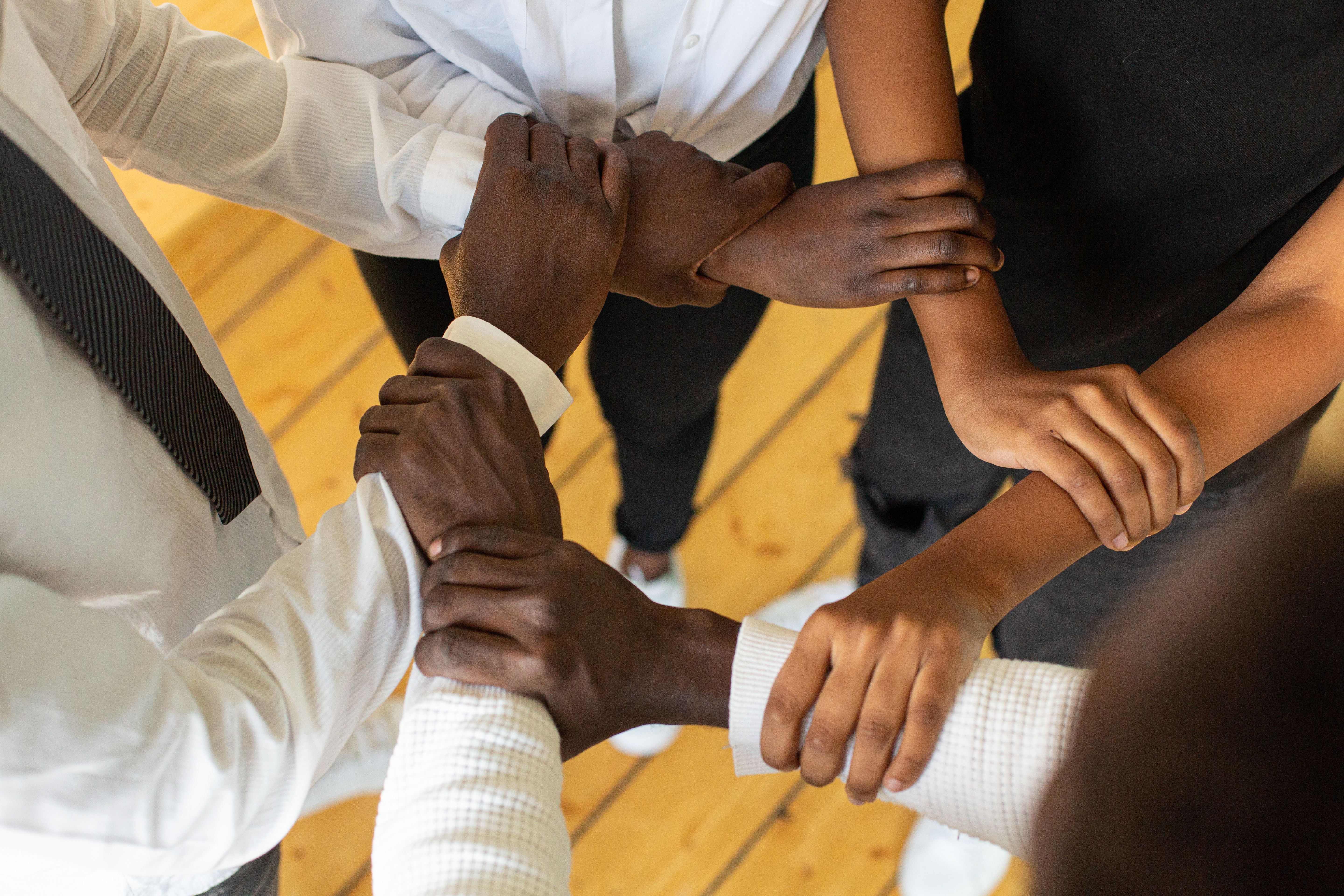 Many hands brought together in the centre of a circle.