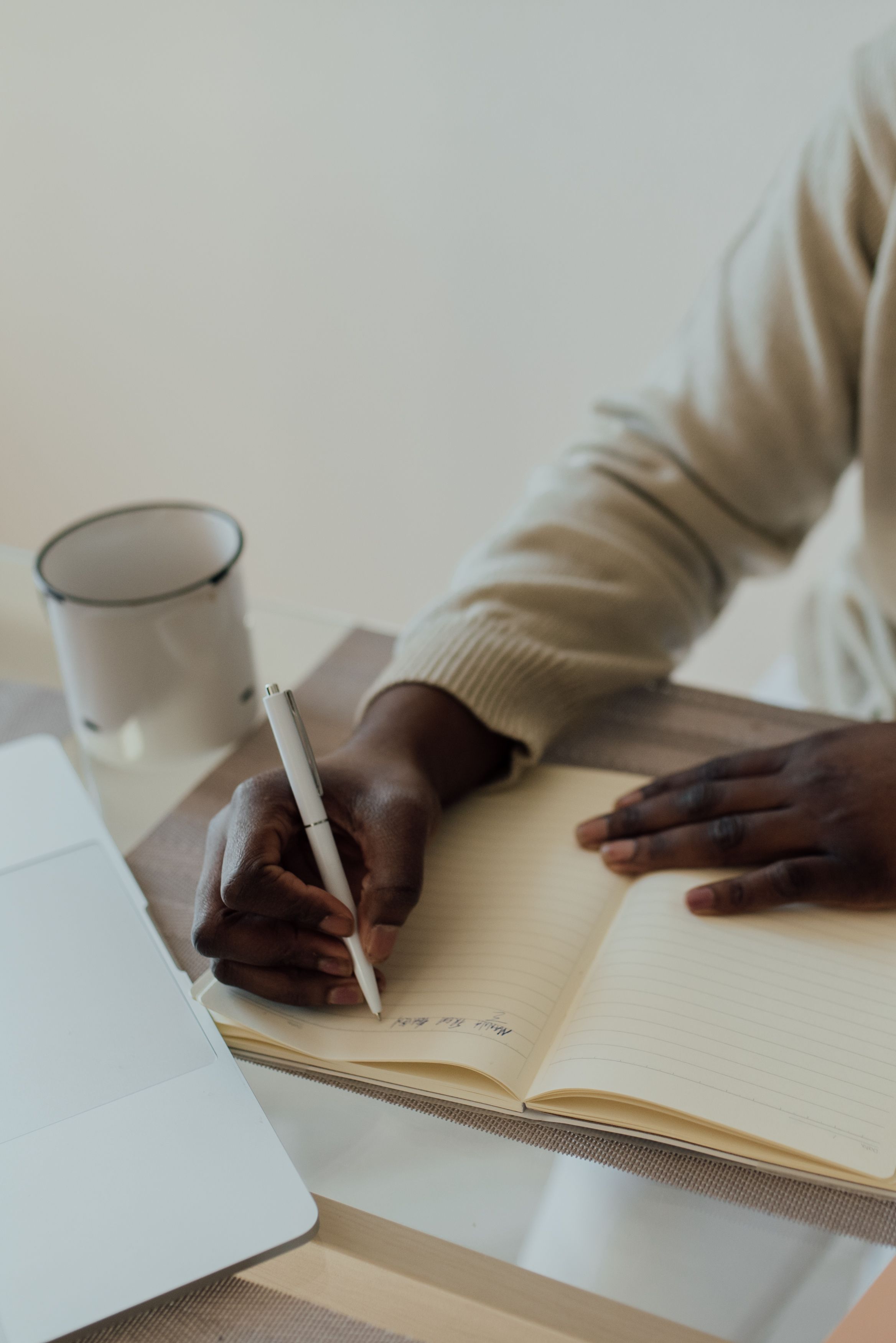 A hand writing in an open notebook in bright daylight.