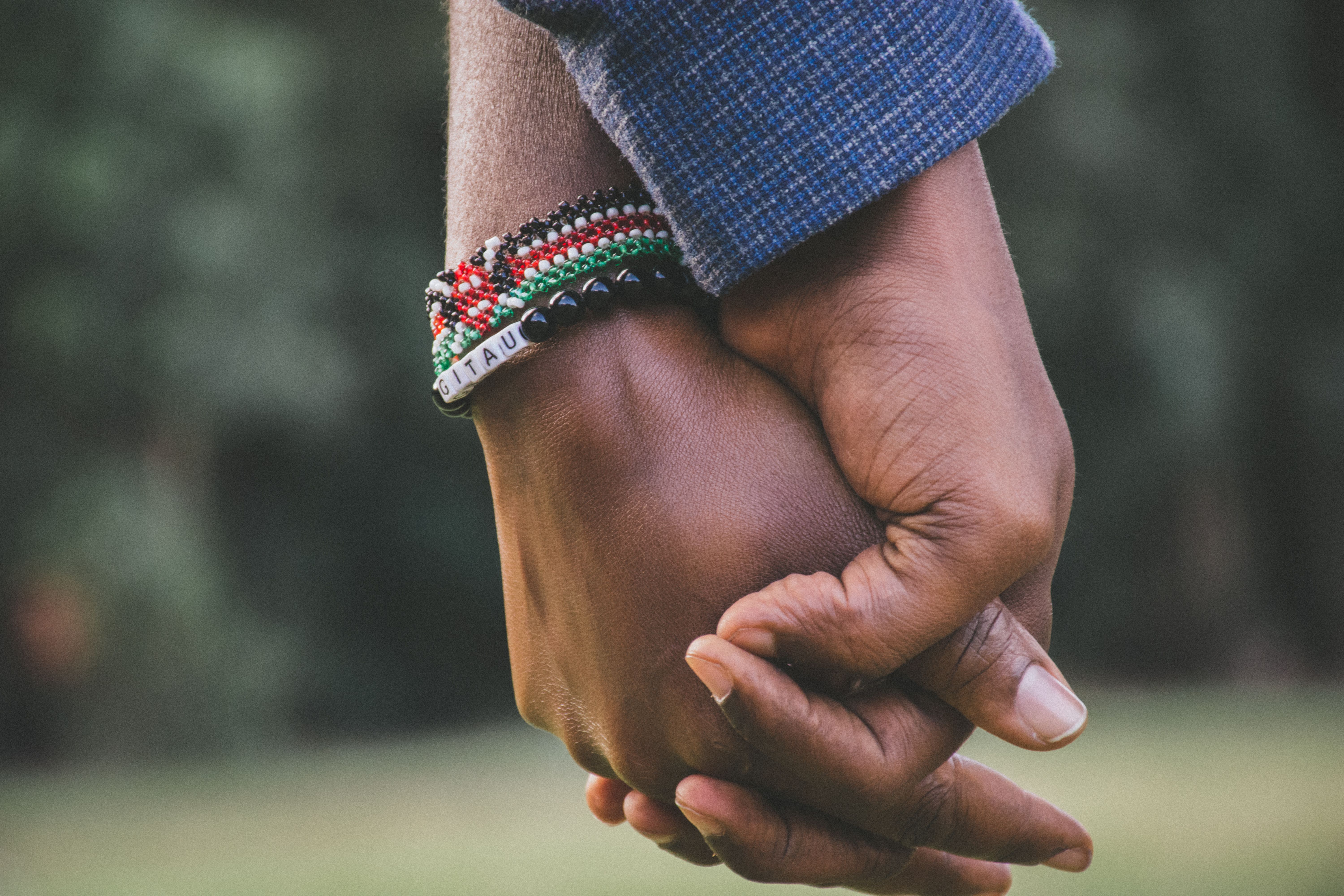 Two people's hands, one holding the other steady against soft daylight.